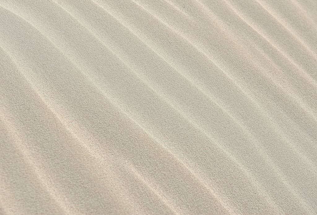 Close-up view of textured sand dunes with soft ripples, perfect for backgrounds.